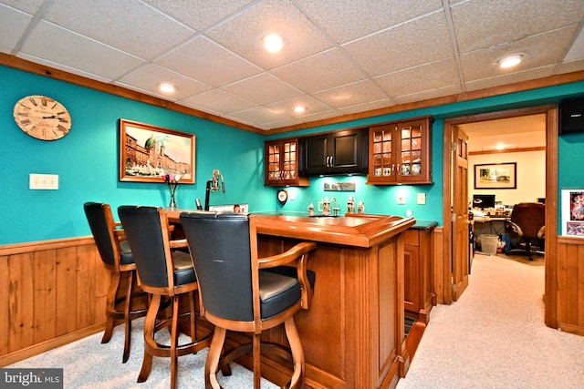 bar featuring recessed lighting, light carpet, wood walls, bar area, and wainscoting