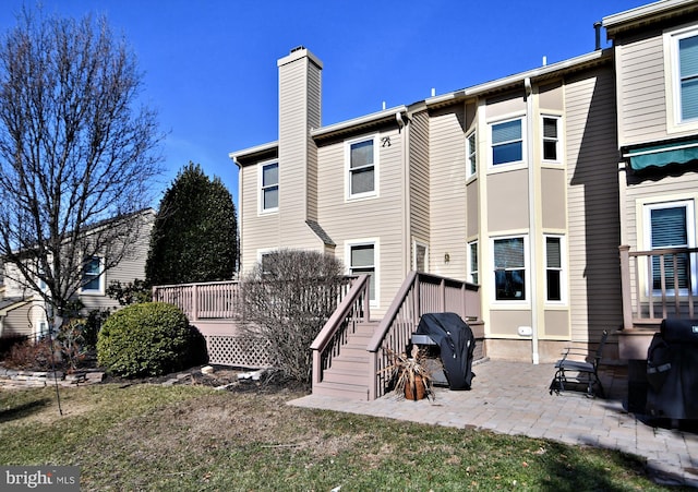 rear view of house with a chimney, a deck, and a patio