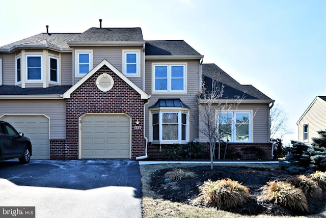 view of front of house with brick siding, driveway, an attached garage, and roof with shingles