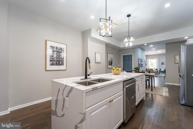 kitchen featuring decorative light fixtures, stainless steel appliances, a sink, open floor plan, and a center island with sink