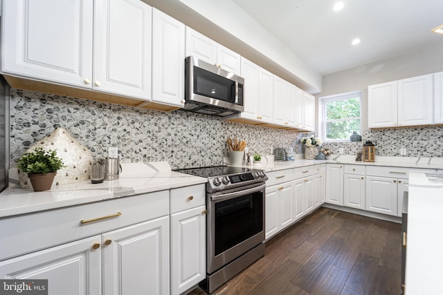 kitchen featuring white cabinets, decorative backsplash, stainless steel appliances, and dark wood finished floors