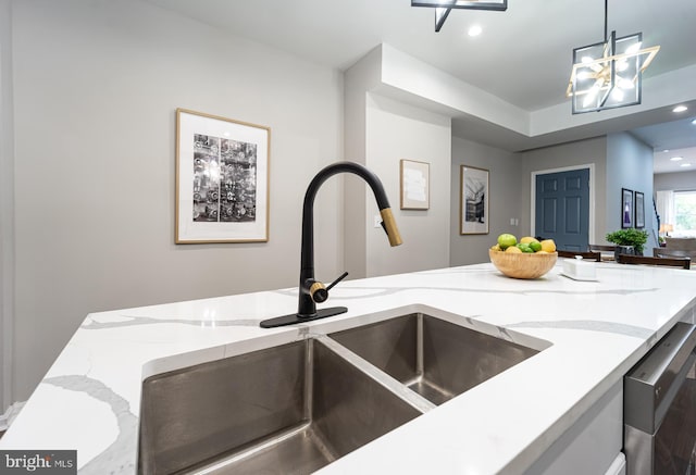 kitchen with dishwasher, light stone countertops, pendant lighting, a sink, and recessed lighting