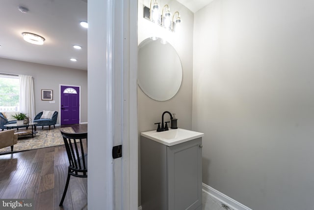 bathroom with wood finished floors, recessed lighting, a sink, and baseboards