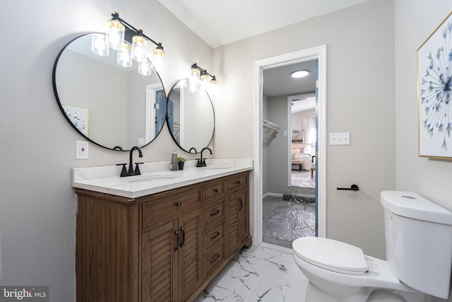 bathroom featuring marble finish floor, double vanity, toilet, ensuite bathroom, and a sink