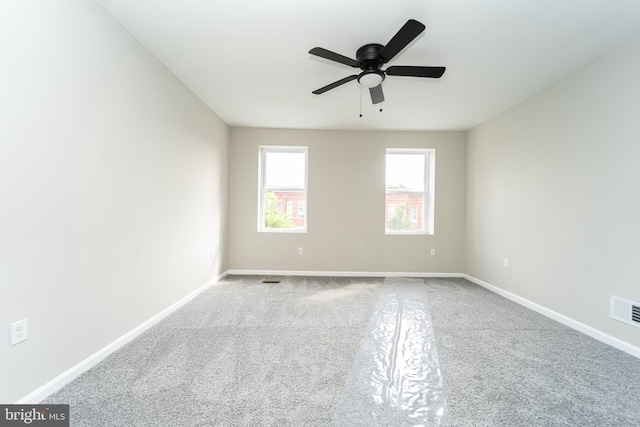 spare room featuring ceiling fan, visible vents, and baseboards