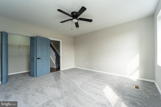 unfurnished bedroom featuring carpet, a closet, visible vents, a ceiling fan, and baseboards