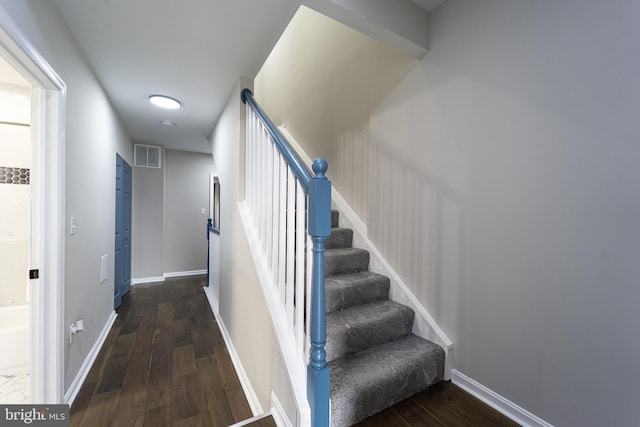 staircase with baseboards, visible vents, and wood finished floors