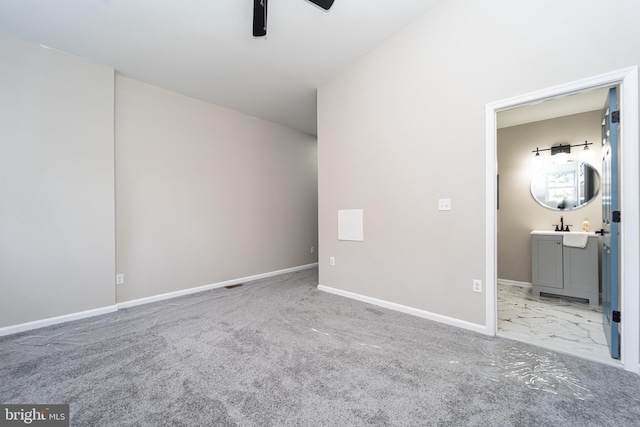 unfurnished bedroom featuring baseboards, ensuite bath, ceiling fan, marble finish floor, and carpet