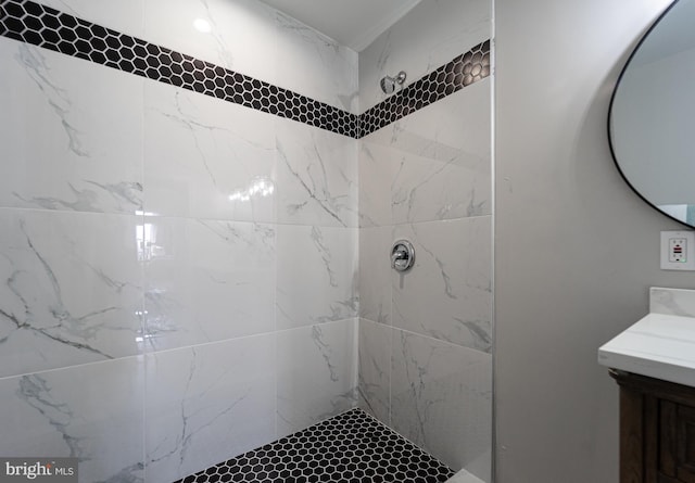 bathroom with a tile shower and vanity