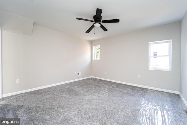 carpeted spare room featuring a ceiling fan and baseboards