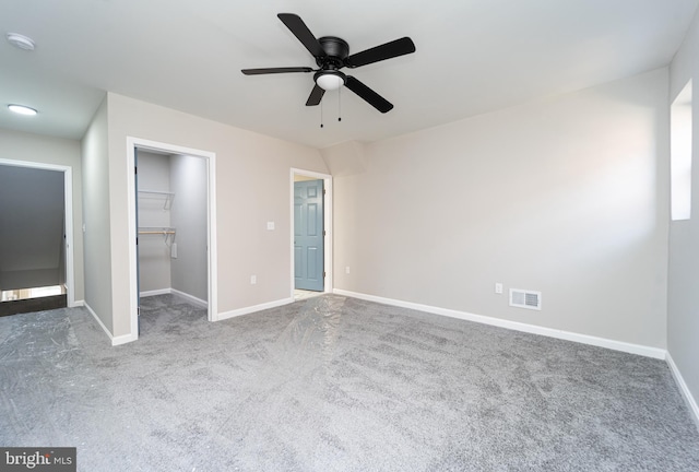 unfurnished bedroom featuring carpet floors, a walk in closet, visible vents, and baseboards