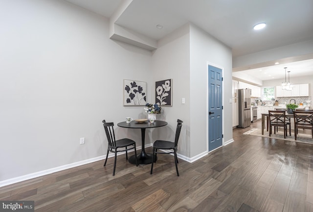 dining space featuring dark wood-style flooring, a notable chandelier, and baseboards