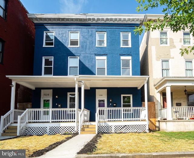 view of property featuring a porch and brick siding