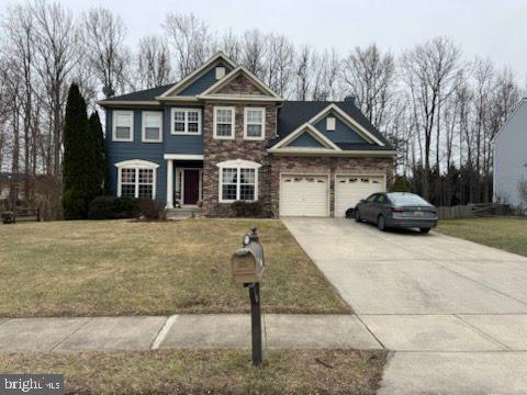 view of front facade featuring an attached garage, driveway, stone siding, and a front yard