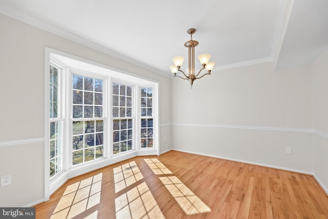 unfurnished dining area with a notable chandelier, crown molding, baseboards, and wood finished floors