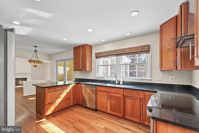 kitchen featuring a sink, light wood-type flooring, a warm lit fireplace, dishwasher, and a peninsula