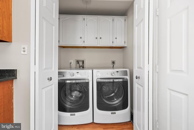 laundry room featuring wood finished floors, washing machine and dryer, and cabinet space