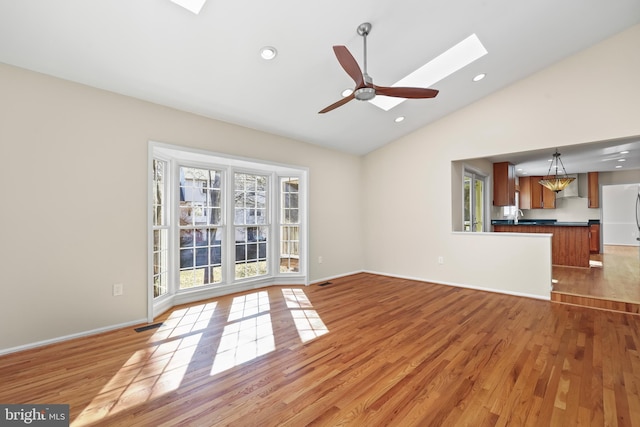 unfurnished living room with light wood-style floors, vaulted ceiling with skylight, a ceiling fan, and recessed lighting