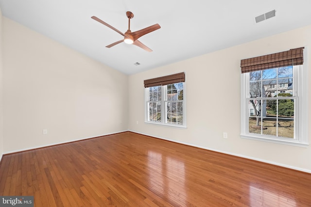 spare room with visible vents, ceiling fan, baseboards, and hardwood / wood-style flooring