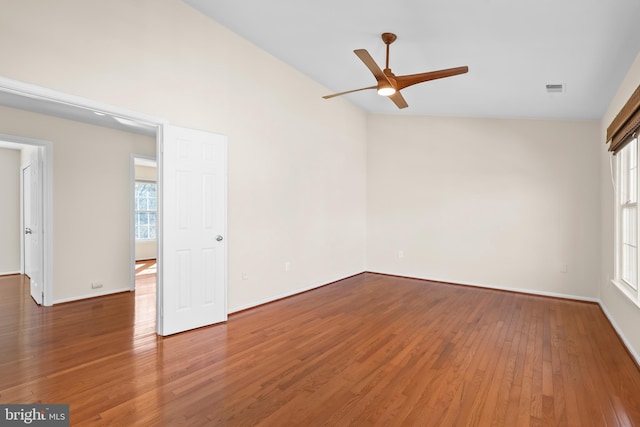 spare room with baseboards, visible vents, ceiling fan, wood finished floors, and vaulted ceiling