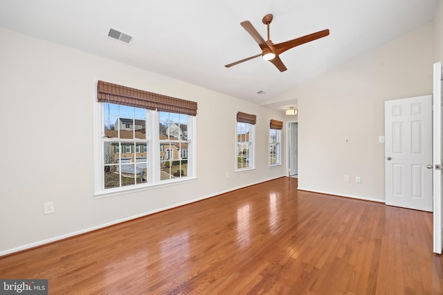 empty room featuring baseboards, visible vents, a ceiling fan, lofted ceiling, and wood finished floors