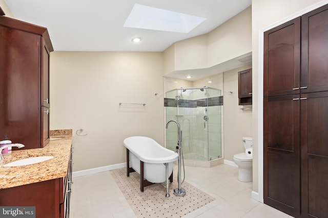 bathroom featuring toilet, a skylight, vanity, baseboards, and a stall shower