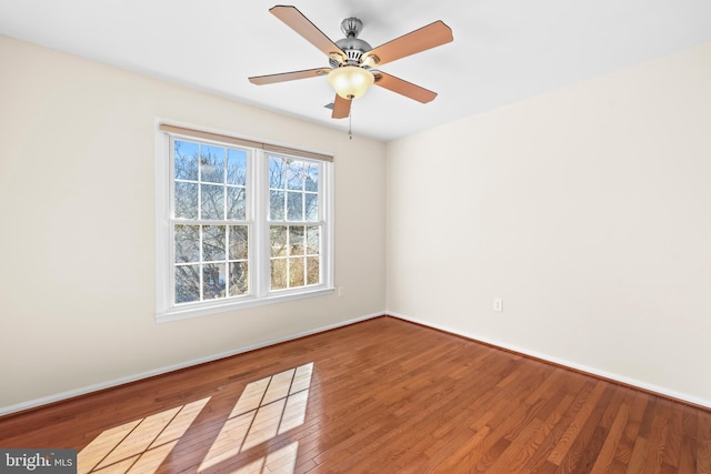 empty room with ceiling fan, wood finished floors, and baseboards