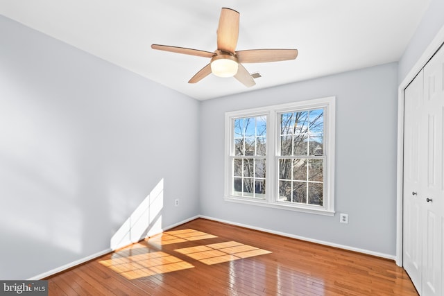 unfurnished bedroom featuring a ceiling fan, wood-type flooring, baseboards, and a closet