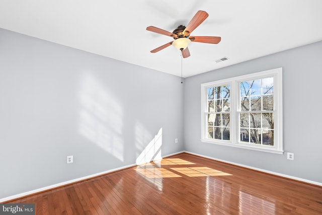 spare room featuring a ceiling fan, wood-type flooring, visible vents, and baseboards