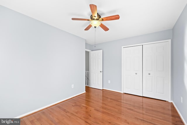 unfurnished bedroom featuring a ceiling fan, a closet, baseboards, and wood finished floors