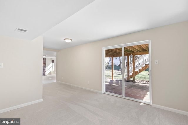 carpeted empty room featuring stairway, visible vents, and baseboards