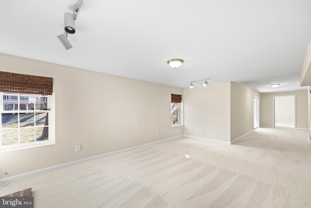 spare room with light carpet, baseboards, and track lighting