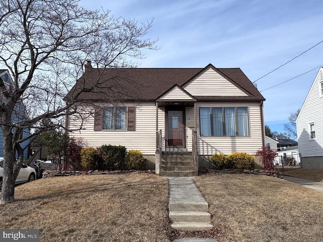 bungalow-style home featuring a shingled roof and a front lawn