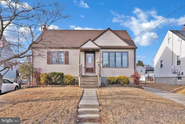 bungalow-style house featuring roof with shingles and a front yard