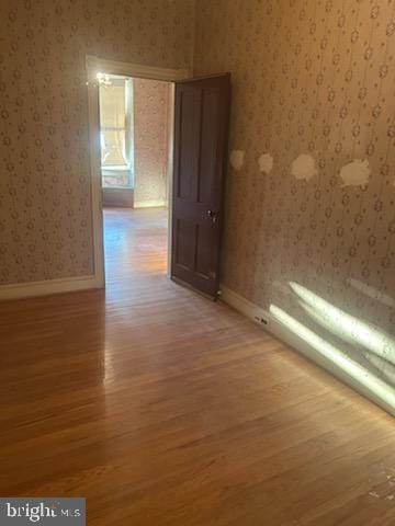 empty room with wallpapered walls, baseboards, and light wood-style floors