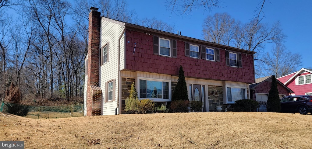 view of front of home with stone siding and a chimney