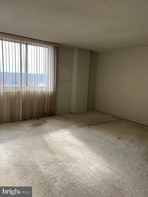 carpeted empty room with a water view and a textured ceiling