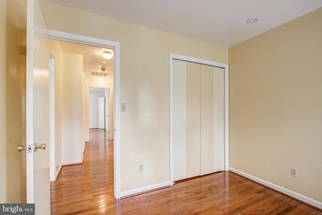 unfurnished bedroom with light wood-style floors, a closet, visible vents, and baseboards