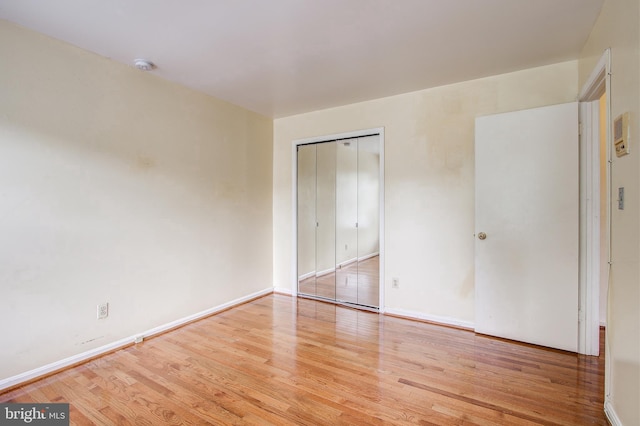 unfurnished bedroom with a closet, baseboards, and wood finished floors