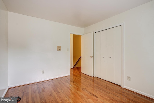 unfurnished bedroom featuring a closet, wood finished floors, and baseboards