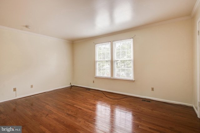 spare room featuring baseboards, wood-type flooring, visible vents, and crown molding