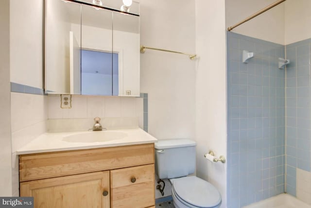 full bath featuring toilet, decorative backsplash, tiled shower, and vanity