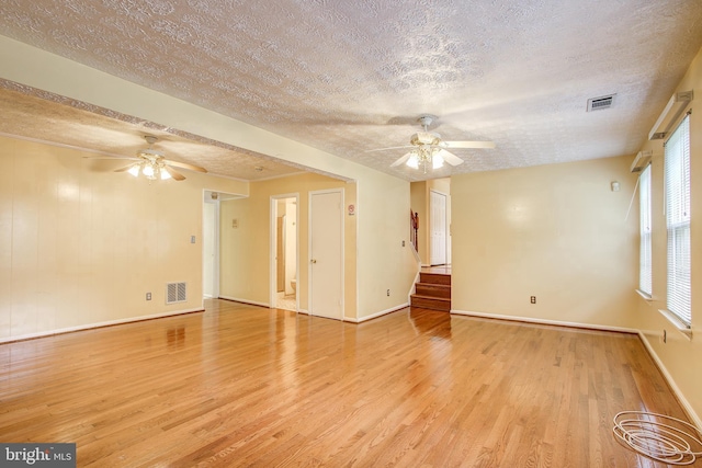 unfurnished living room featuring light wood-type flooring, visible vents, and a ceiling fan