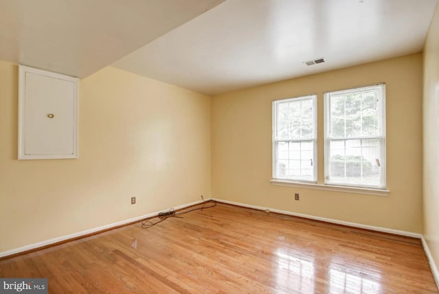 spare room with visible vents, baseboards, and wood finished floors