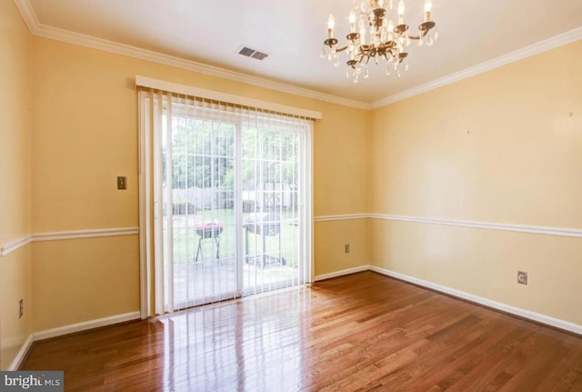 spare room featuring baseboards, visible vents, ornamental molding, wood finished floors, and an inviting chandelier