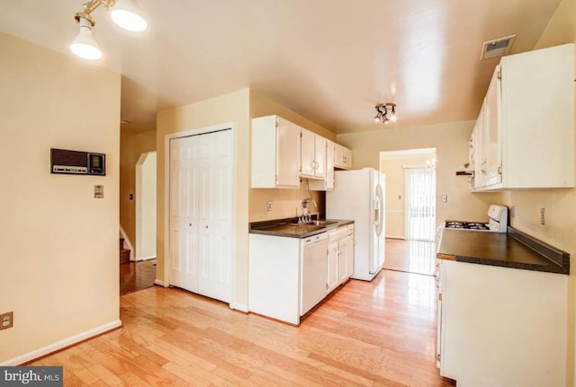 kitchen with dark countertops, white appliances, visible vents, and white cabinetry