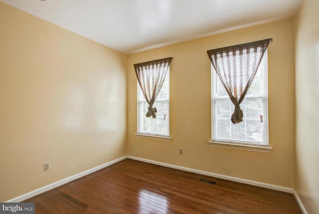 unfurnished room featuring visible vents, baseboards, and hardwood / wood-style flooring