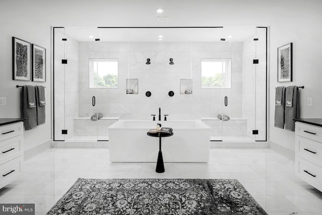 bathroom featuring marble finish floor, a freestanding tub, vanity, and a shower stall