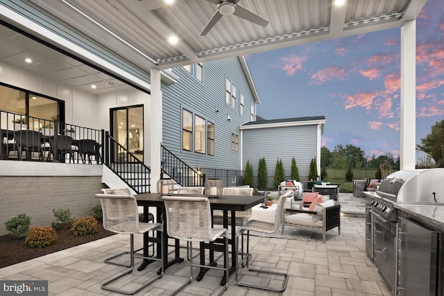 view of patio featuring grilling area, outdoor dining space, fence, exterior kitchen, and stairs