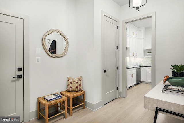 corridor featuring light wood-style flooring and baseboards